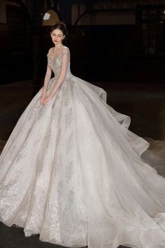 a woman in a white wedding dress standing on the floor with her hands behind her back