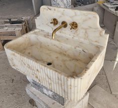 a white marble sink with gold faucet and matching faucets on it