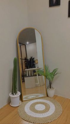 a mirror sitting on top of a wooden table next to a potted plant