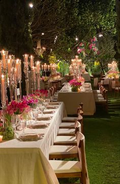 a long table is set up with candles and flowers in vases for an outdoor dinner