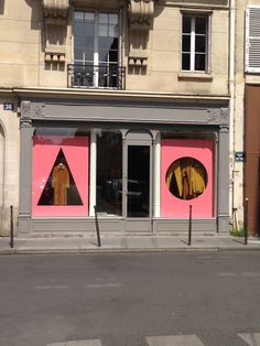 an empty street in front of a building with pink and yellow decorations on the windows