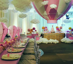 a table set up for a baby shower with pink and white balloons in the background