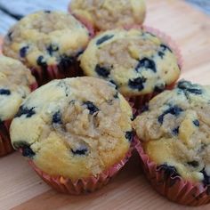 several blueberry muffins sitting on top of a wooden cutting board