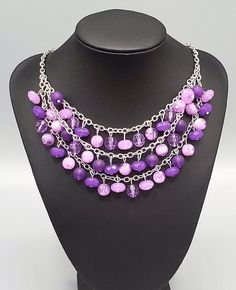 "Fairytale Timelessness": Varying in shape and opacity, a mismatched collection of light and dark purple crystal-like beads drip from the shimmery silver chains, creating an enchanted layered fringe below the collar. Features an adjustable clasp closure. Sold as one individual necklace. Includes one pair of matching earrings. Purple Dangling Beads Jewelry For Party, Purple Beaded Chain Jewelry For Party, Purple Party Necklace With Chain Detail, Purple Chain Necklace For Party, Purple Faceted Beads Jewelry For Party, Purple Jewelry With Faceted Beads For Party, Lavender Dangling Beads For Jewelry Making, Adjustable Purple Beaded Dangle Necklaces, Purple Party Jewelry With Adjustable Chain