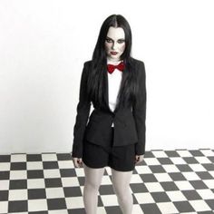 a woman dressed in black and white poses for a photo on a checkered floor