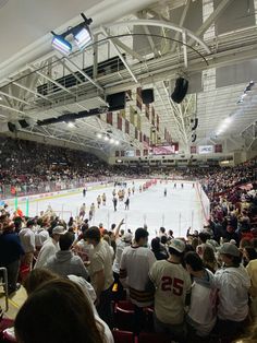 an ice hockey game is being played in a large indoor arena with people watching from the stands