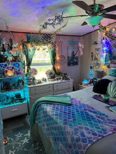 a bedroom decorated in blue and green with mermaid themed decorations on the ceiling, bedding, and dressers