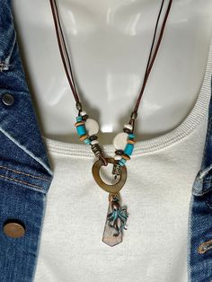 Detailed Picasso Jasper pendant hangs Lariat style with Turquoise, White and Turquoise Bone, Wood beads and a Mother of Pearl Loop to close. All on 2 leather cords, a 1mm dark brown and 2mm distressed brown. Picasso Jasper pendant is 1 1/2" long and 1/2" wide, around neck is 22" and total length of necklace is 24". A turquoise patina Octopus charm to the side that can be deleted of changed if you wish. To wear place open necklace around neck then put pendant thru the MOP ring. Adjust at will. No lead or nickel used. Please use the Last On, First Off approach. Stones discolor with lotions, perfumes, hairspray, sweat, chlorine, even some soaps, and will break if dropped. Adjustable Bohemian Turquoise Necklace, Turquoise Bohemian Necklace With Adjustable Length, Bohemian Turquoise Necklace With Adjustable Length, Turquoise Bohemian Lariat Necklace As Gift, Bohemian Dangle Turquoise Necklace With Adjustable Fit, Bohemian Lariat Necklace With Adjustable Pendant, Turquoise Bohemian Lariat Necklace For Gift, Bohemian Lariat Necklace With Adjustable Cord, Bohemian Turquoise Lariat Necklace Gift