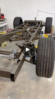 a car being worked on in a garage by someone working on the front wheel and suspensions