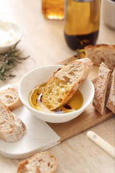 a bowl of soup on a cutting board with bread and olive oil next to it