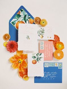 the stationery is laid out on top of each other with oranges and flowers