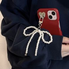 a woman holding a red cell phone case with a bow charm on it's side