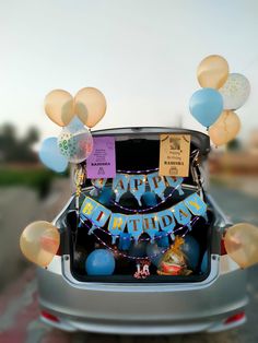 an open car trunk with balloons and streamers on the back, along with a happy birthday sign