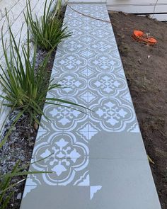 a cement walkway with an intricate design painted on the side and grass growing next to it