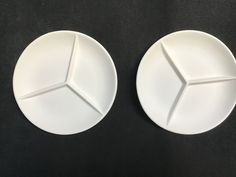 two white plates sitting next to each other on a black counter top with the same design on them