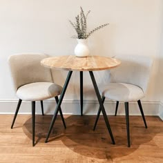 two chairs sitting at a table with a vase on top of it next to each other