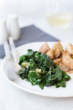 a white plate topped with greens and meat