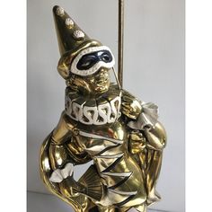 a statue of a man dressed in gold and wearing a party hat, holding a stick