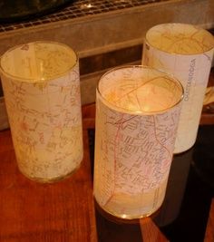 three candles with maps on them sitting on a table