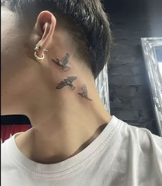 a man with a small bird tattoo on his left side of the neck and behind his ear