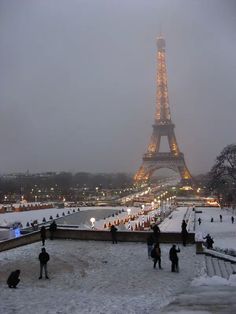 the eiffel tower is lit up at night in paris, on a snowy day