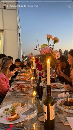 a group of people sitting at a long table with food and drinks in front of them