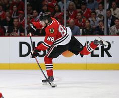 a hockey player in red jersey and black pants skating on the ice