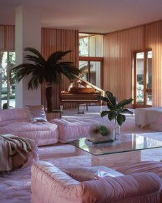 a living room filled with pink couches and a grand piano in the back ground