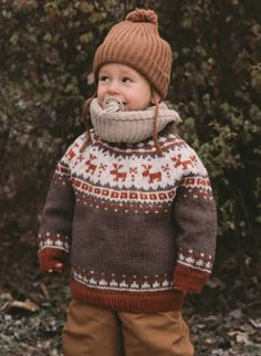 a little boy wearing a sweater and hat