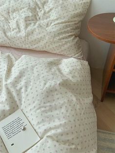 a book is laying on top of the bed with white sheets and polka dot print