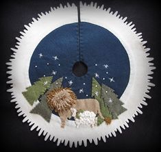 a felt decoration with a lion and trees in the middle on a black background,