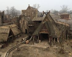 an old village with thatched roofs and stone buildings in the foreground, surrounded by bare trees