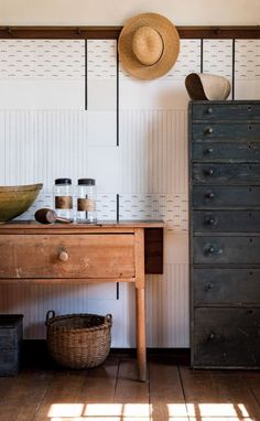 an old dresser with two jars and a hat on it's head next to a wall