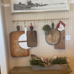 three wooden cutting boards hanging on the wall above a shelf with utensils and other kitchen items