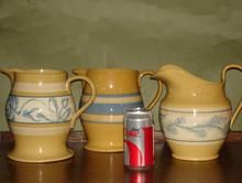 four pitchers and two cans on a table