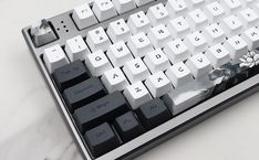 a computer keyboard sitting on top of a white table next to a black and white mouse