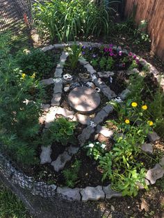 a garden with rocks and flowers in the center, surrounded by fenced in plants