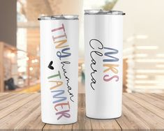 two personalized stainless steel tumblers sitting on top of a wooden table