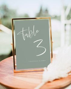 a table number is displayed on a wooden stand with white feathers in the foreground