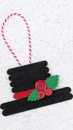 an ornament made out of popsicle sticks with holly leaves and red buttons