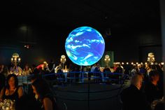 a group of people sitting at tables in front of a large globe with the earth on it