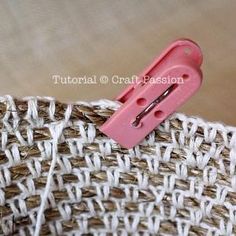 a pink pin is stuck to the side of a piece of woven material that has been stitched together