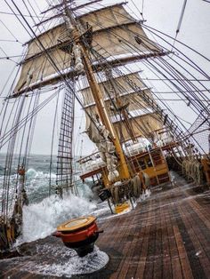 an old sailing ship in rough seas on a cloudy day with waves crashing against the deck