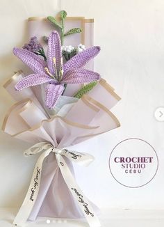 a bouquet of purple flowers is wrapped in brown paper and tied with white satin ribbon