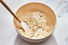 a bowl filled with food and a wooden spoon sitting on top of a counter next to it