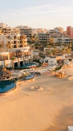 an aerial view of a beach resort with several pools and hotels in the background,