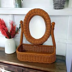 a wicker basket sitting on top of a wooden table next to a vase with flowers