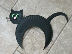 a paper plate cat with green eyes on the floor