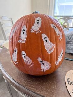 a pumpkin decorated with white ghost faces on it's side sitting on a table