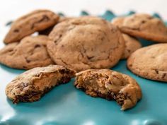 chocolate chip cookies and one half eaten cookie on a blue platter with white polka dots